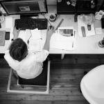 black and gray photo of person in front of computer monitor