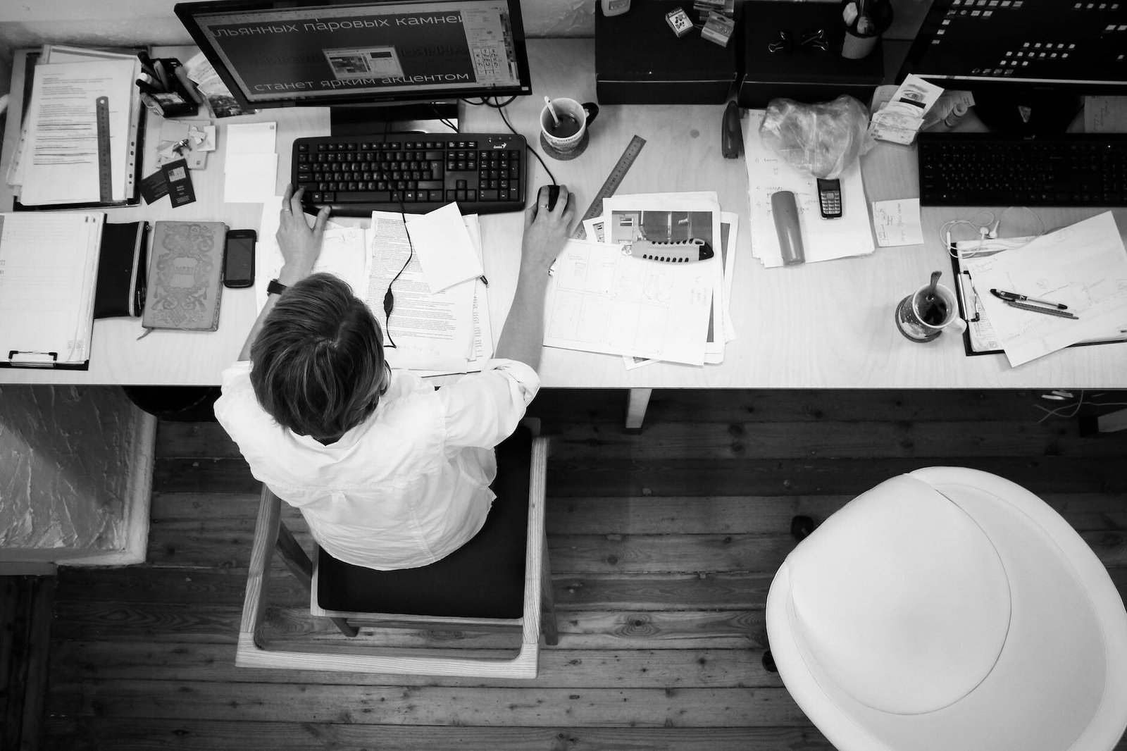 black and gray photo of person in front of computer monitor